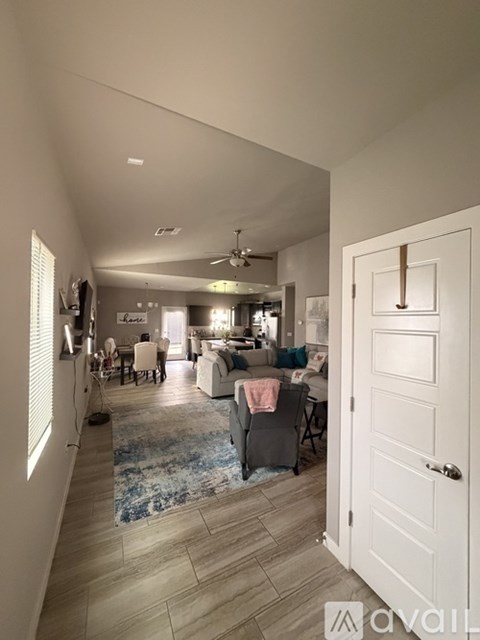 A living room with a rug and a ceiling fan.