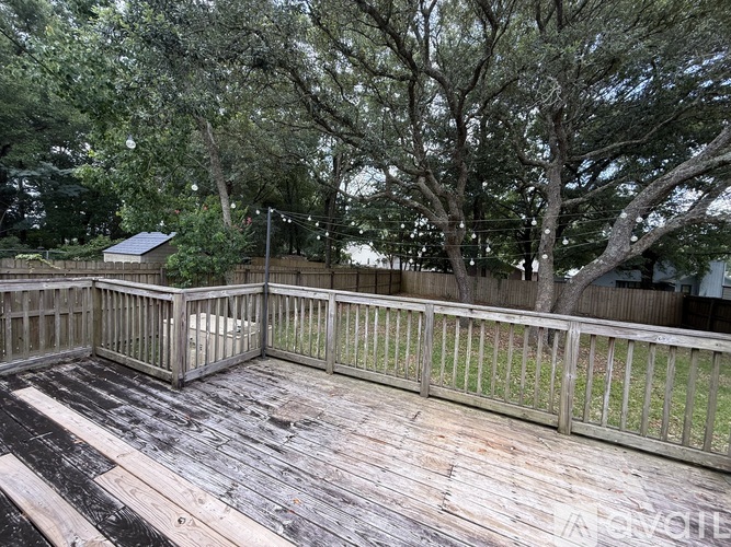 A wooden deck with a railing and trees in the background.