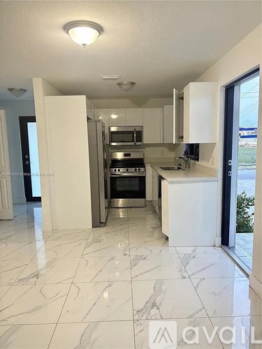 A kitchen with white cabinets and marble flooring.