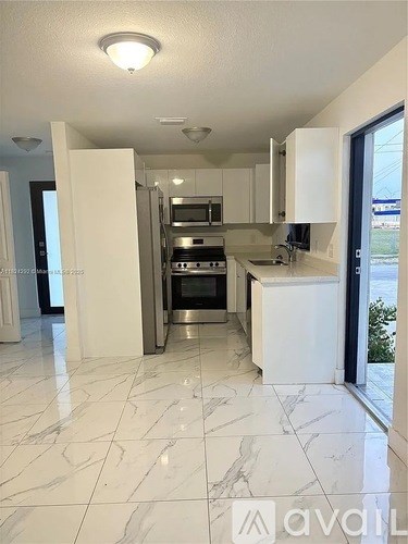 A kitchen with white cabinets and marble flooring.