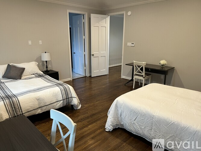 A bedroom with two beds and a desk.