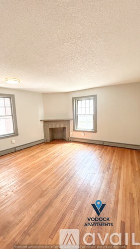 A room with wooden floors and a fireplace is available for rent.