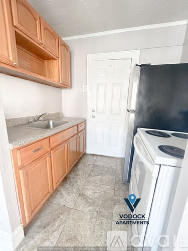 A kitchen with wooden cabinets and a black refrigerator.