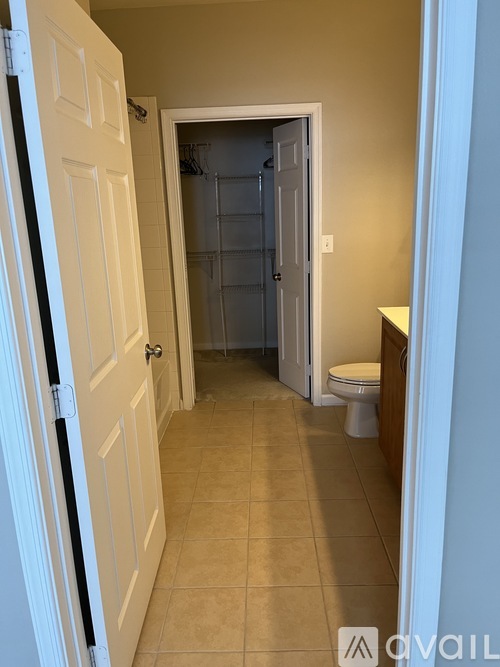 A white door is open to a small bathroom with a toilet and a walk-in shower.