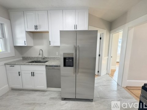 A kitchen with white cabinets and a stainless steel refrigerator.