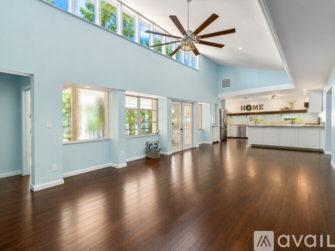 A spacious room with wooden floors and a ceiling fan.