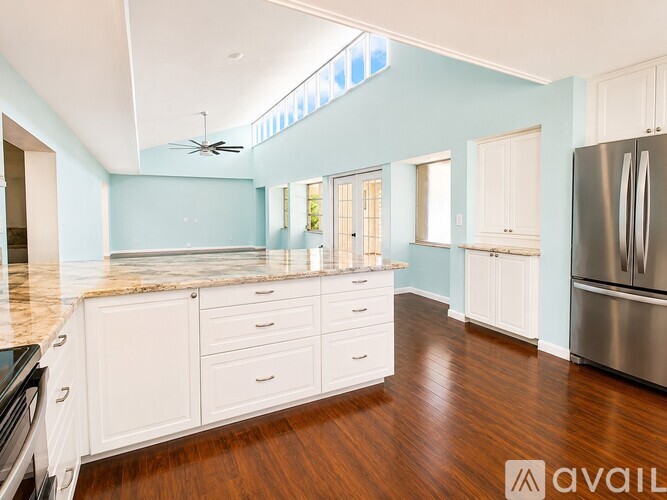 A kitchen with white cabinets and a marble countertop.