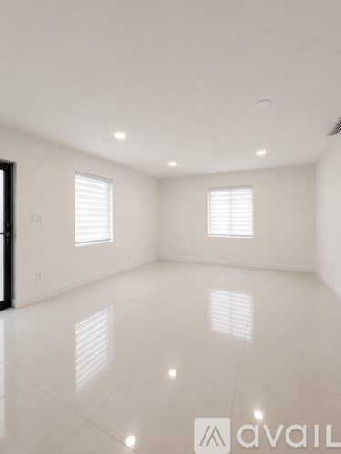 A spacious room with white flooring and two windows.