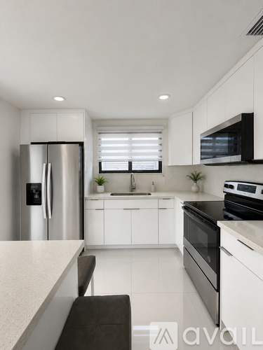 A modern kitchen with white cabinets and stainless steel appliances.