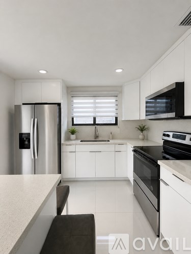 A modern kitchen with white cabinets and stainless steel appliances.
