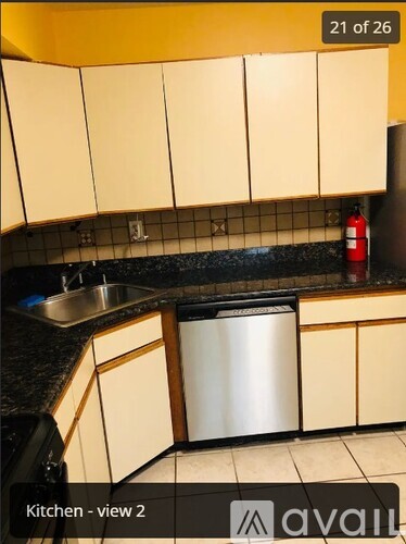 A kitchen with beige cabinets and a black countertop.