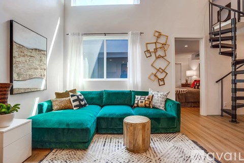 A living room with a green couch and a wooden stool.