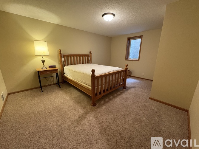 A bedroom with a bed, nightstand, and window.
