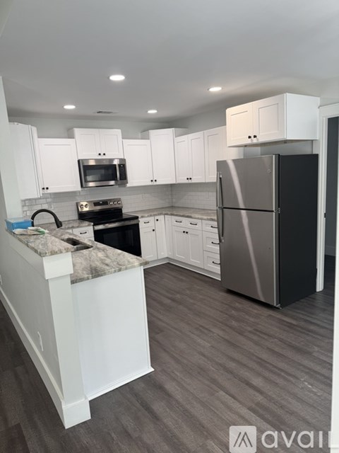 A kitchen with a black refrigerator and white cabinets.