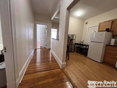 A long hallway with wood floors and white walls.