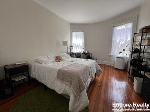 A bedroom with a bed, nightstand, and window.
