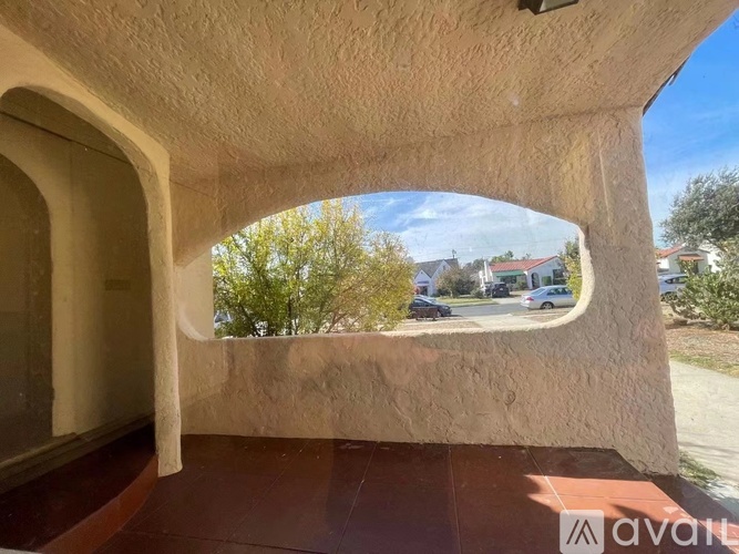 A view from a window with a curved wall and a tree in the distance.