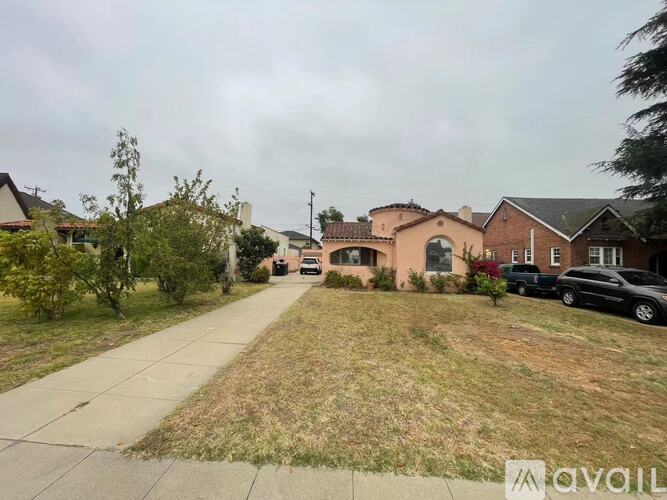 A residential street with houses on both sides and cars parked in front.