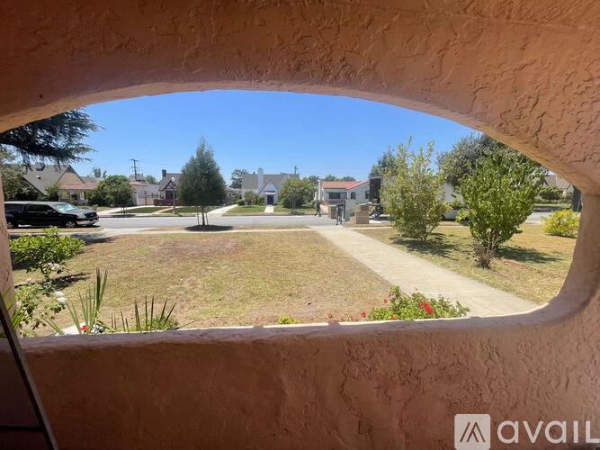 A view from a window looking out onto a grassy area with a house in the distance.