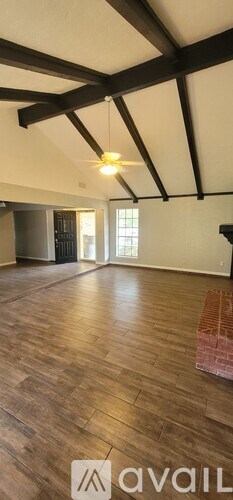 A spacious room with wooden floors and a high ceiling with exposed beams.