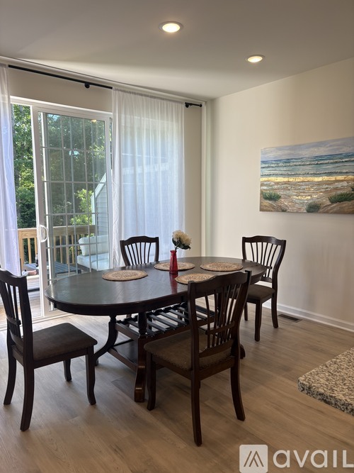 A dining room with a table set for four and a painting on the wall.