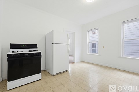 A kitchen with a black stove and white refrigerator in a white room.
