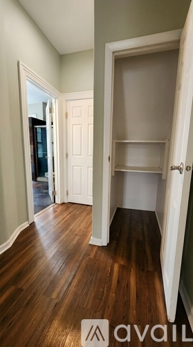A hallway with a white door and a wooden floor.