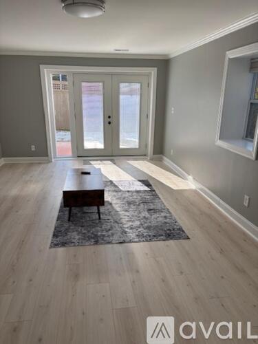 A spacious room with a wooden floor and a rug in the center.