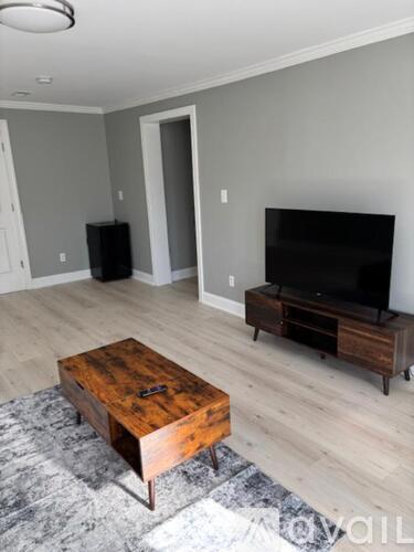 A living room with a wooden coffee table and a flat screen TV on a wooden stand.