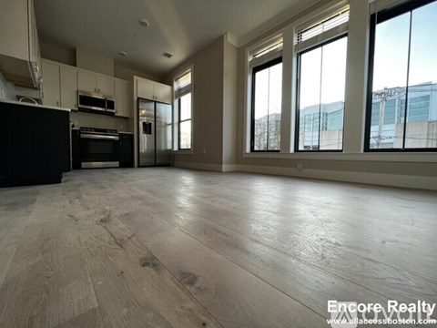 A spacious kitchen with wood flooring and large windows.