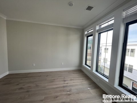 A room with wooden flooring and large windows.