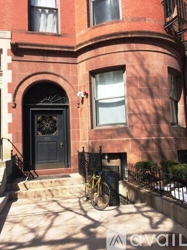 A red brick building with a black door and a bicycle leaning against the fence.