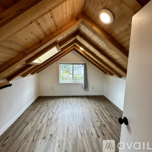 A room with wooden floors and a window with a view of trees.
