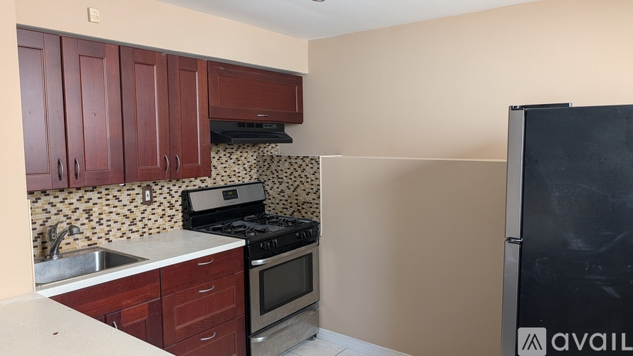A kitchen with wooden cabinets and a black fridge.