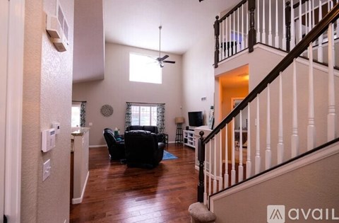 A living room with a black couch and a ceiling fan.