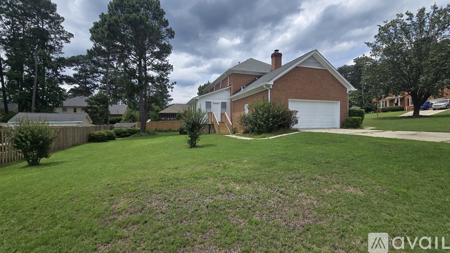 A house with a large lawn and trees in the background.