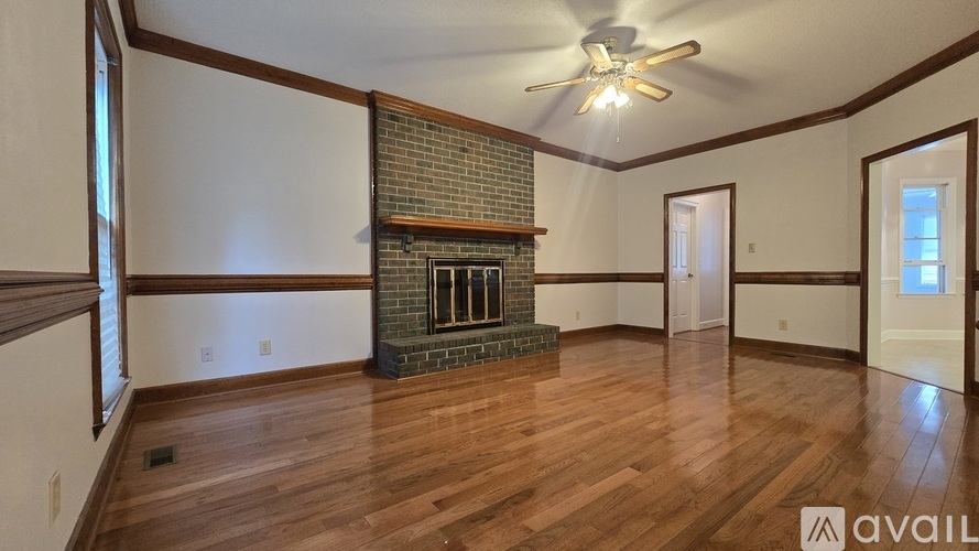 A living room with wood flooring and a brick fireplace.