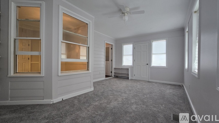 A spacious room with a carpeted floor and a ceiling fan.