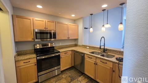 A kitchen with wooden cabinets and stainless steel appliances is available for rent.