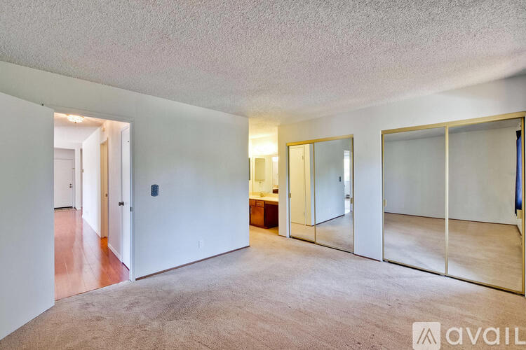 A spacious room with a carpeted floor and a large mirror on the wall.