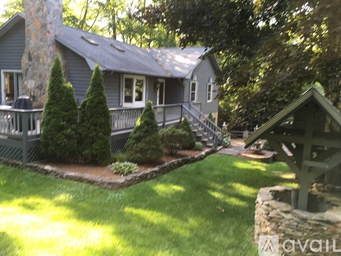 A house with a stone chimney and a deck with a railing.