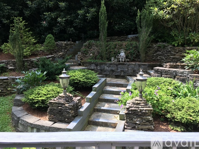 A stone staircase with a lamp post on each side leads up to a lush green garden.