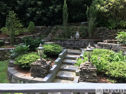 A stone staircase with a lamp post on each side leads up to a lush green garden.