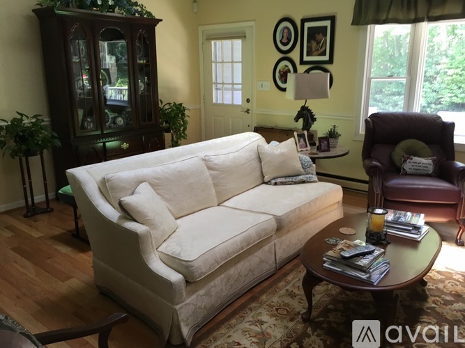 A living room with a white couch, a brown armchair, and a wooden cabinet.