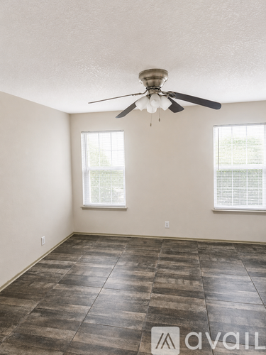 A room with a ceiling fan and two windows.