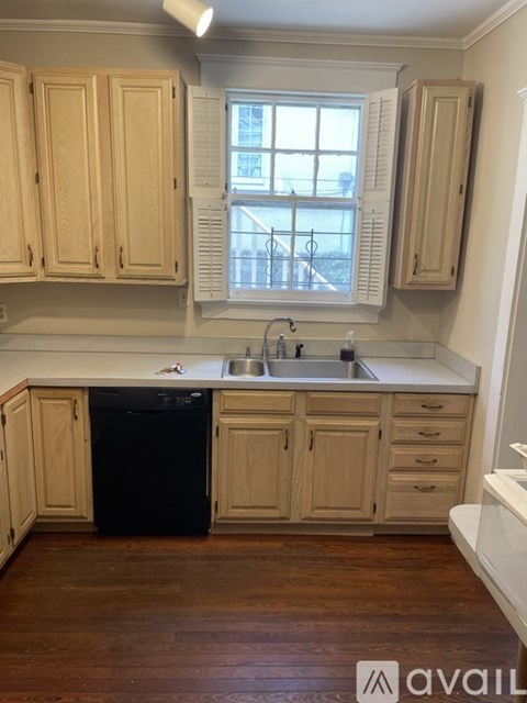 A kitchen with wooden cabinets and a black dishwasher.