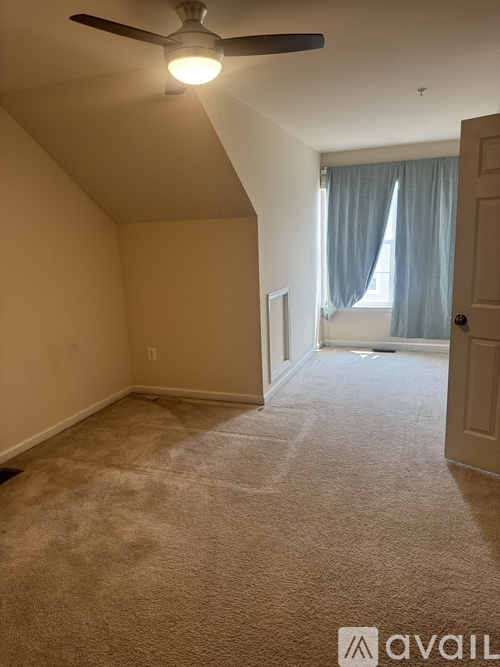 A room with a carpeted floor and a ceiling fan.