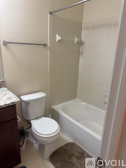 A white toilet and bathtub in a bathroom with a white tiled wall.