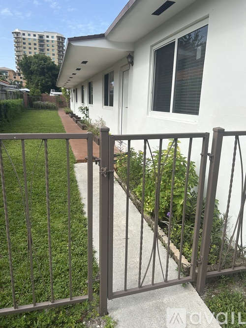 A white house with a metal fence and a small garden.