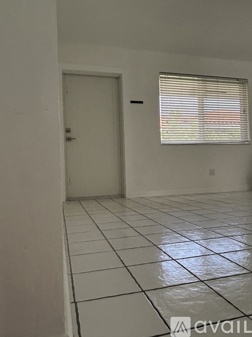A room with a white door and a window with blinds.